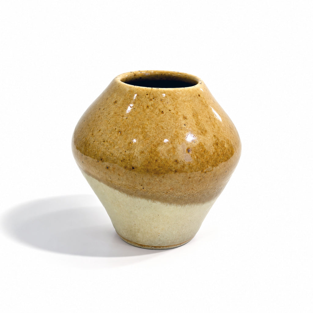 A small ceramic bud vase with a rounded bulbous shape, featuring a glossy two-tone glaze that transitions from a warm brown at the top to a light cream at the bottom, set against a plain white background.