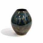 A glossy ceramic vase with a rounded, bulbous shape, featuring a mottled glaze of dark blue, teal, and brown with a subtle metallic sheen, set against a plain white background.