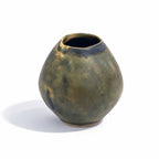 A small rounded ceramic vase with a wide opening, featuring a mottled earthy green and brown glaze with dark blue-brown accents near the rim, set against a plain white background.