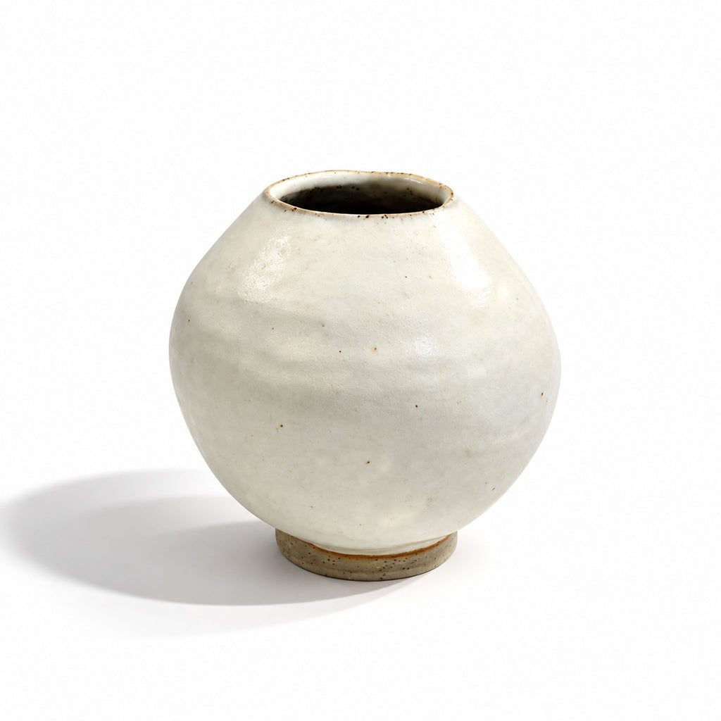 A small round ceramic vase with a matte off-white glaze and a natural brown clay foot, photographed on a clean white background.